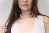 A woman wearing a white dress and a choker 10 mm pearl necklace 