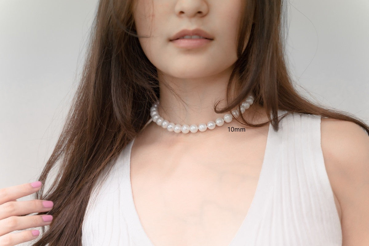A woman wearing a white dress and a choker 10 mm pearl necklace 