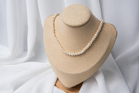 A white 4 mm pearl choker necklace with a sterling silver chain, displayed on a necklace display stand