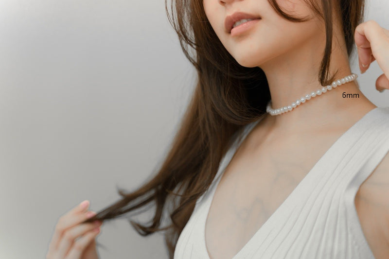 A woman wearing a white dress and a choker 6 mm pearl necklace 