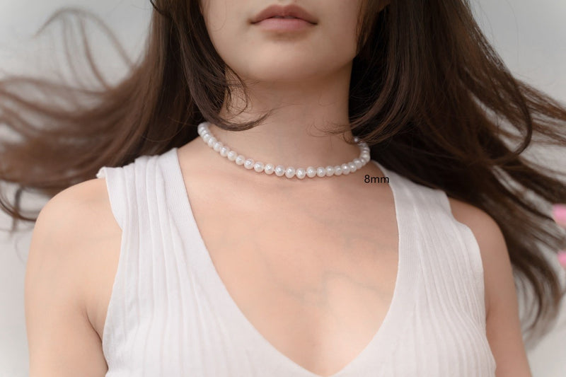 A woman wearing a white dress and a choker 8 mm pearl necklace 