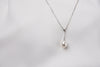 A classic drop pearl necklace with a silver chain and a white pearl pendant, displayed on a neutral background.
