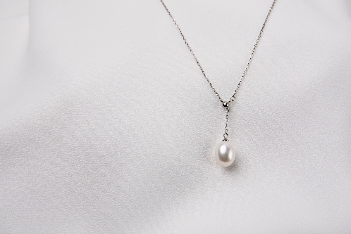 A classic drop pearl necklace with a silver chain and a white pearl pendant, displayed on a neutral background.