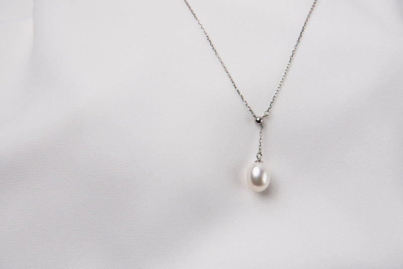 A classic drop pearl necklace with a silver chain and a white pearl pendant, displayed on a neutral background.