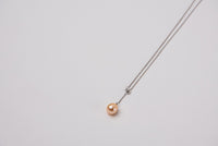 A classic drop pearl necklace with a silver chain and a champagne pearl pendant, displayed on a neutral background.