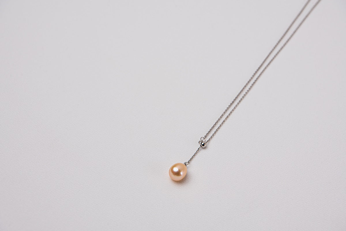 A classic drop pearl necklace with a silver chain and a champagne pearl pendant, displayed on a neutral background.