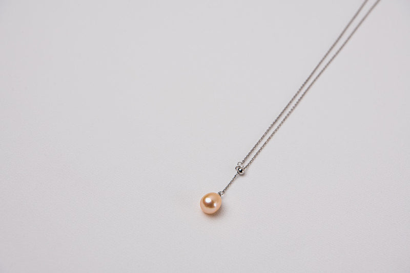 A classic drop pearl necklace with a silver chain and a champagne pearl pendant, displayed on a neutral background.