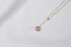 A classic drop pearl necklace with a gold chain and a lavender pearl pendant, displayed on a neutral background.
