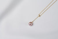 A classic drop pearl necklace with a gold chain and a lavender pearl pendant, displayed on a neutral background.