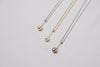 A classic drop pearl necklace with a gold and silver chain and a white ,champagne and lavender pearl pendant, displayed on a neutral background.