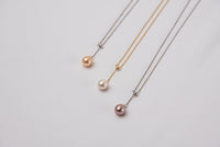 A classic drop pearl necklace with a gold and silver chain and a white ,champagne and lavender pearl pendant, displayed on a neutral background.