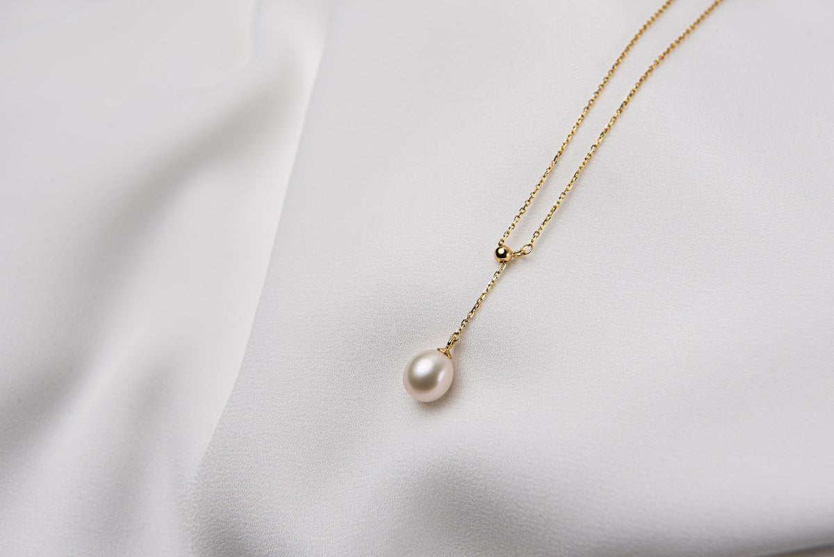 A classic drop pearl necklace with a gold chain and a white pearl pendant, displayed on a neutral background.