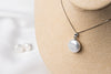 A sterling silver necklace with a white pearl pendant and a box chain style, displayed on a mannequin bust.