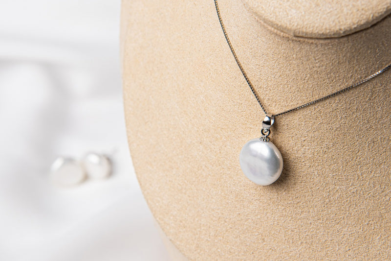 A sterling silver necklace with a white pearl pendant and a box chain style, displayed on a mannequin bust.