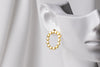 A pair of gold vermeil stud earrings, displayed on a metal earring stand against a white background