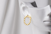 A pair of gold vermeil stud earrings, displayed on a metal earring stand against a white background