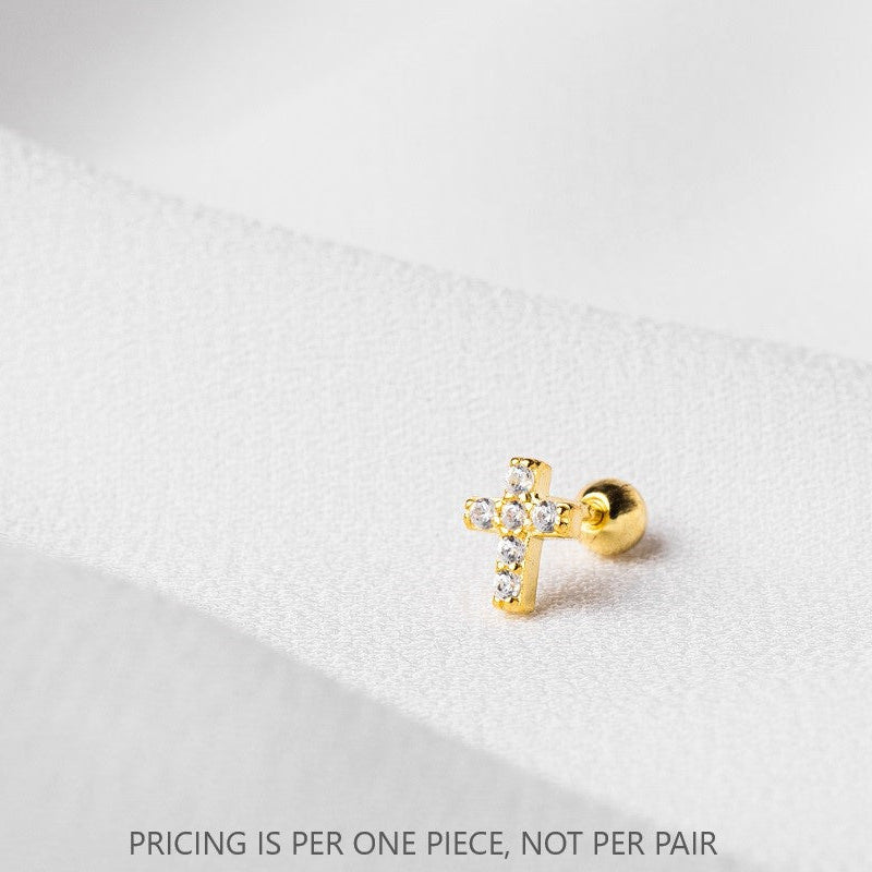 A single gold-colored cross-shaped stud piercing on a white textured background, with a caption that says 'PRICING IS PER ONE PIECE, NOT PER PAIR'.