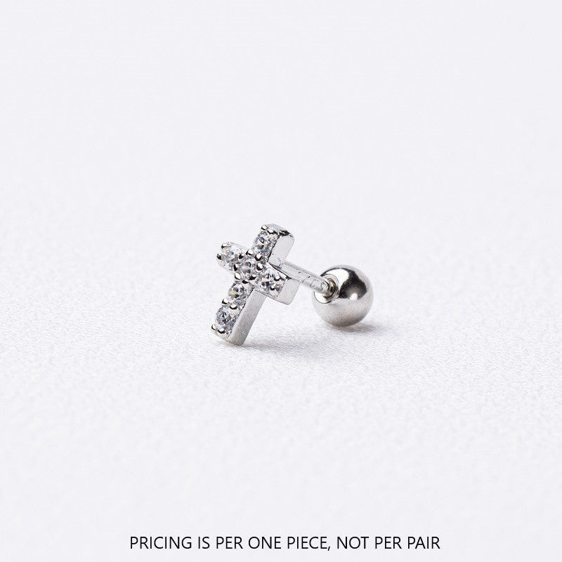 Silver earring with a cross design on a light gray background