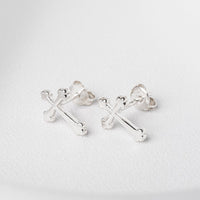 A pair of sterling silver stud earrings with a cross design and butterfly backs, displayed on a white surface.