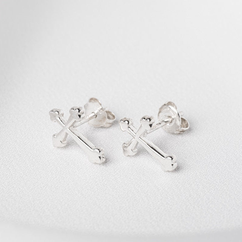 A pair of sterling silver stud earrings with a cross design and butterfly backs, displayed on a white surface.