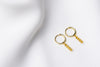 A pair of gold vermeil hoop earrings with a dangle of yellow cubic zirconias on a white fabric surface.