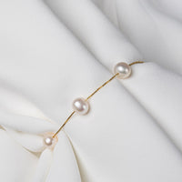 A fine gold chain bracelet featuring 3 white pearls