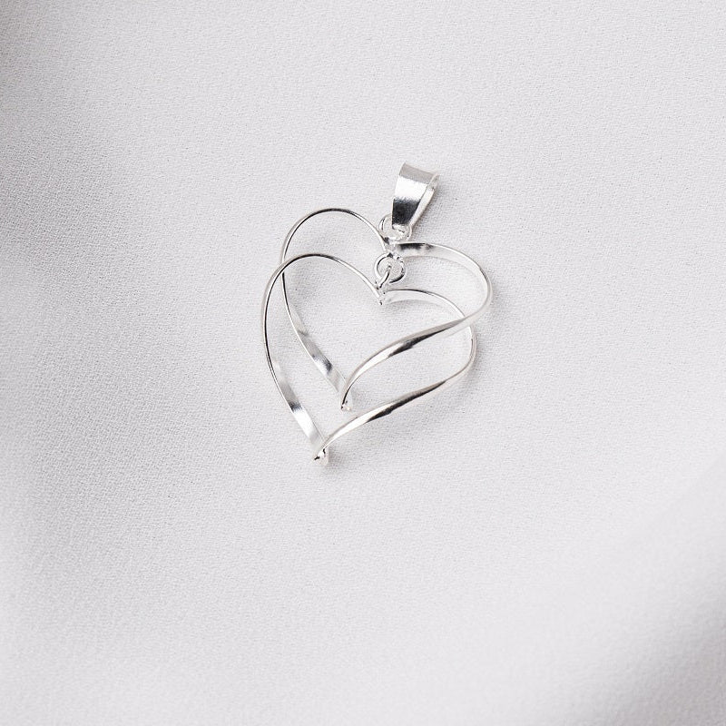 A sterling silver double heart pendant on a white fabric surface