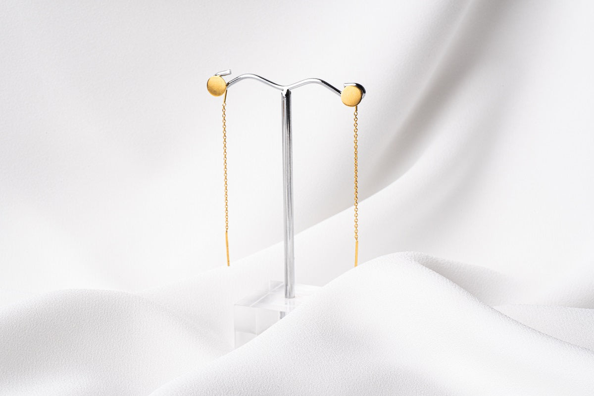 A pair of dangle earrings with a drop tail, butterfly backs, and a silver-colored post on a white stand against a white backdrop.