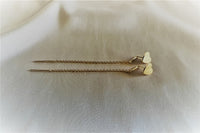 A pair of dangle earrings with a drop tail, butterfly backs, on a textured white background