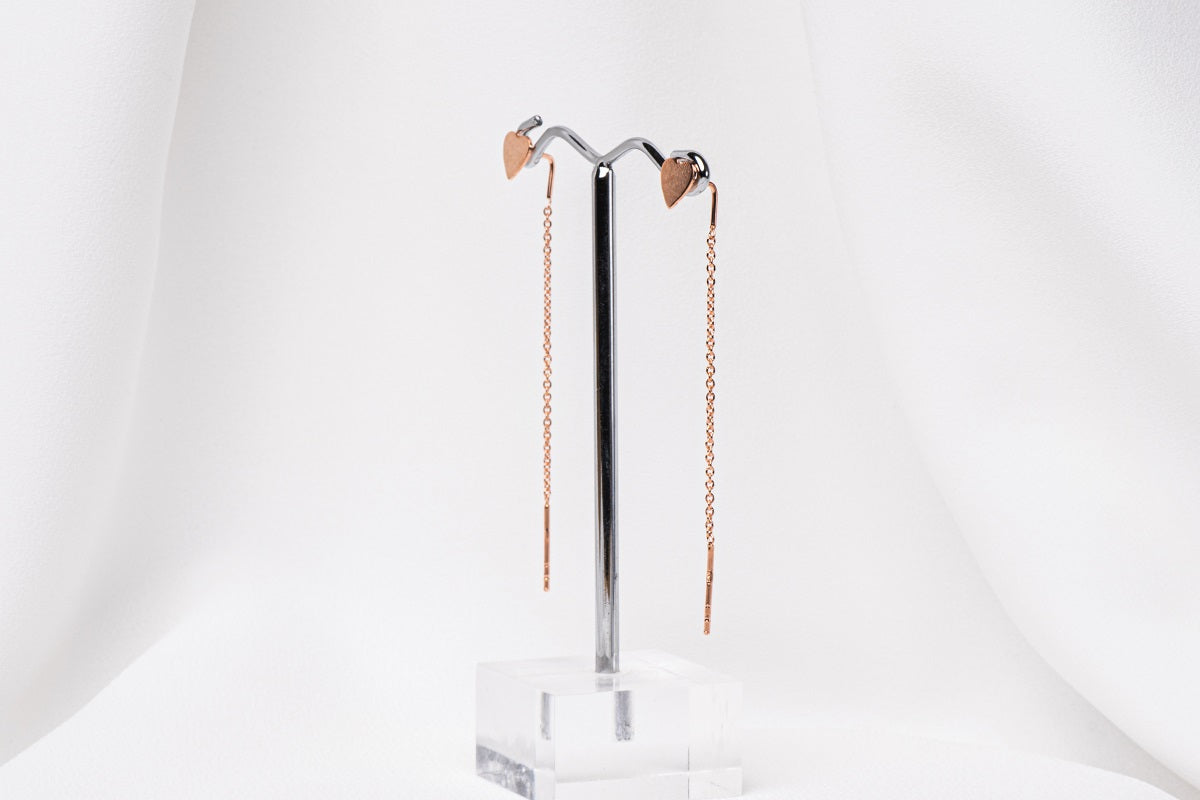 A pair of dangle earrings with a drop tail, butterfly backs, and a silver-colored post on a white stand against a white backdrop.