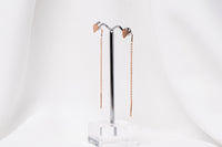 A pair of dangle earrings with a drop tail, butterfly backs, and a silver-colored post on a white stand against a white backdrop.