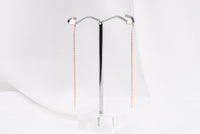 A pair of dangle earrings with a drop tail, butterfly backs, and a silver-colored post on a white stand against a white backdrop.