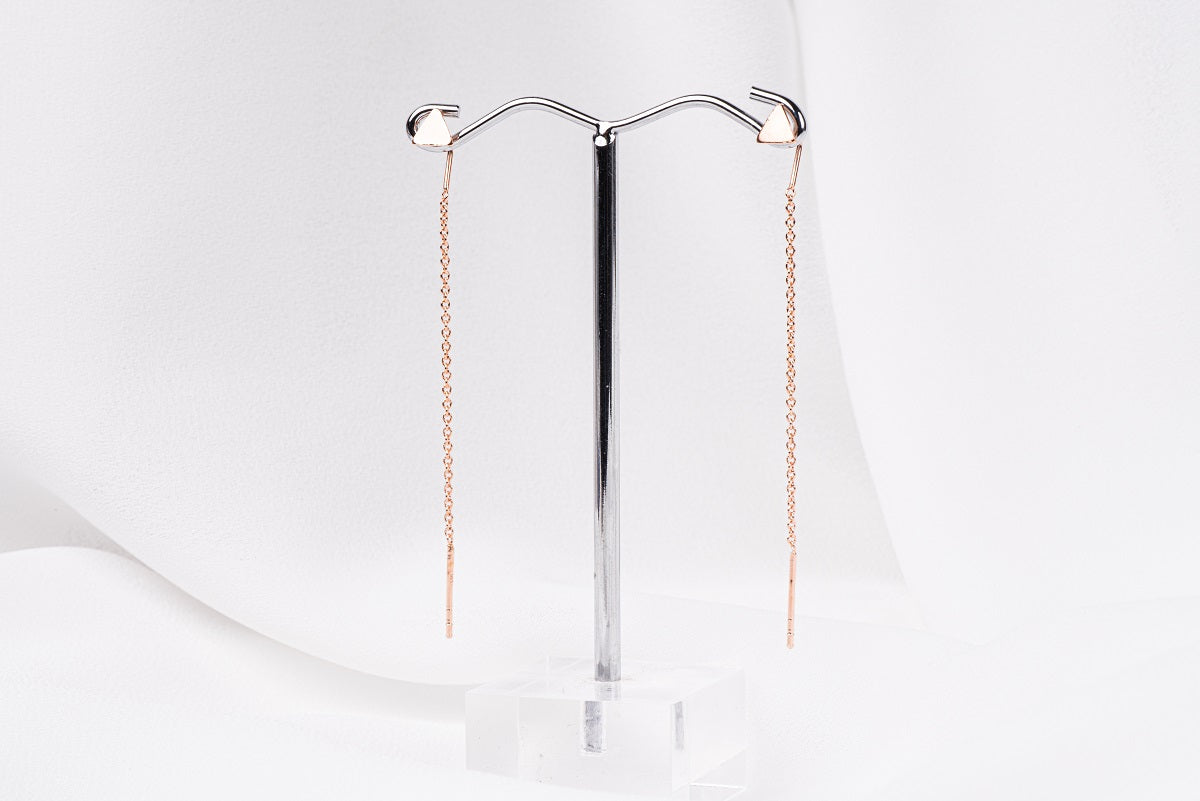 A pair of dangle earrings with a drop tail, butterfly backs, and a silver-colored post on a white stand against a white backdrop.