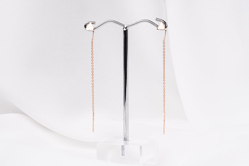 A pair of dangle earrings with a drop tail, butterfly backs, and a silver-colored post on a white stand against a white backdrop.
