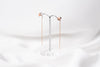 A pair of dangle earrings with a drop tail, butterfly backs, and a silver-colored post on a white stand against a white backdrop.