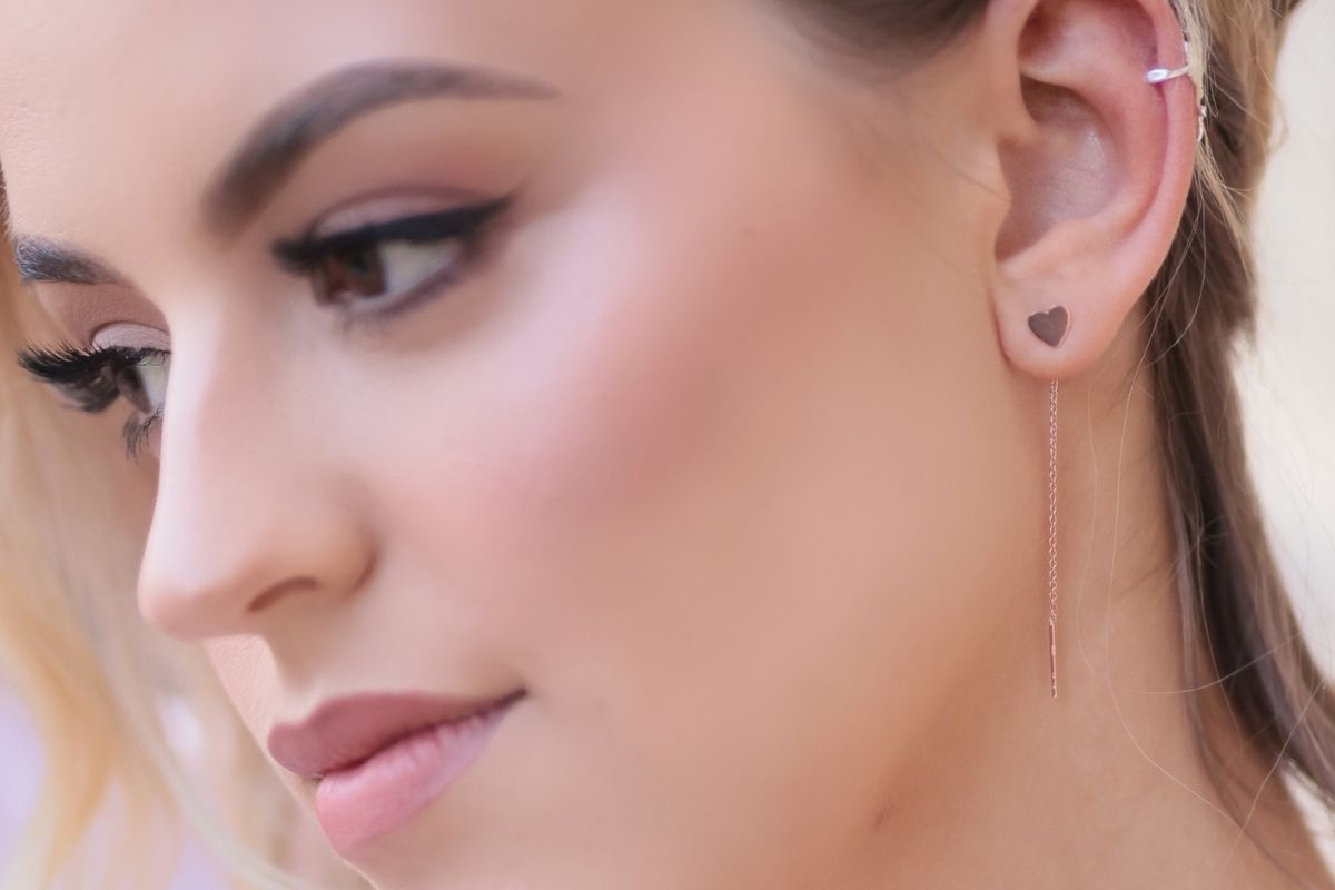 A pair of dangle earrings with a drop tail, butterfly backs, shown on a model.