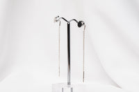 A pair of dangle earrings with a drop tail, butterfly backs, and a silver-colored post on a white stand against a white backdrop.