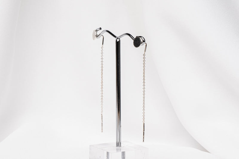A pair of dangle earrings with a drop tail, butterfly backs, and a silver-colored post on a white stand against a white backdrop.