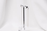 A pair of dangle earrings with a drop tail, butterfly backs, and a silver-colored post on a white stand against a white backdrop.