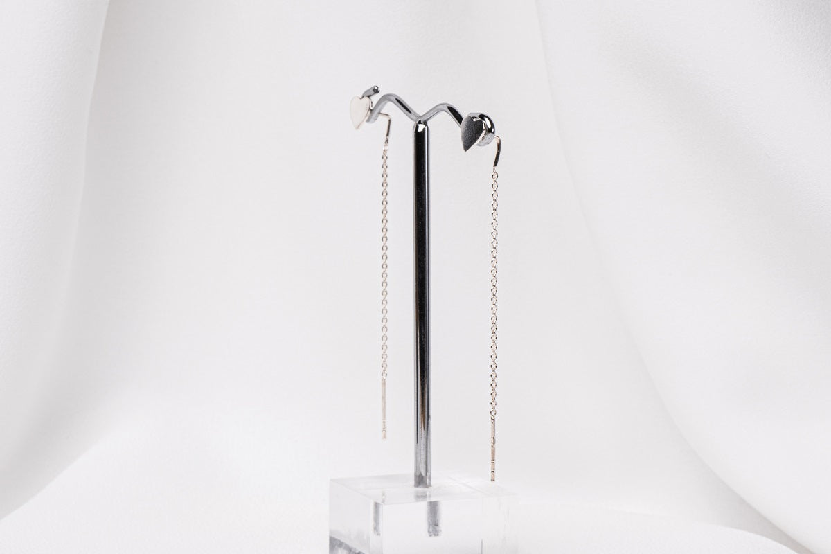 A pair of dangle earrings with a drop tail, butterfly backs, and a silver-colored post on a white stand against a white backdrop.