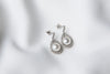 A pair of silver Encanto pearl earrings displayed on a white background.