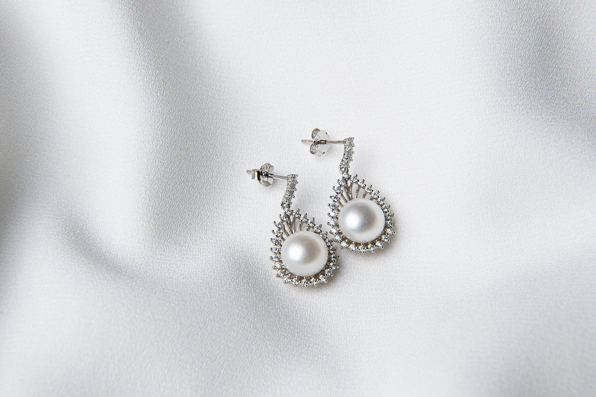 A pair of silver Encanto pearl earrings displayed on a white background.