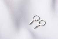 A pair of silver hoop earrings with feather charms displayed on a white background.