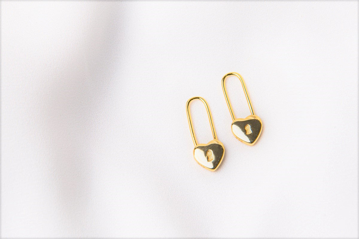 A pair of gold heart lock shaped earrings on a white background
