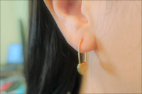 A gold vermeil heart lock shaped earrings on a woman model