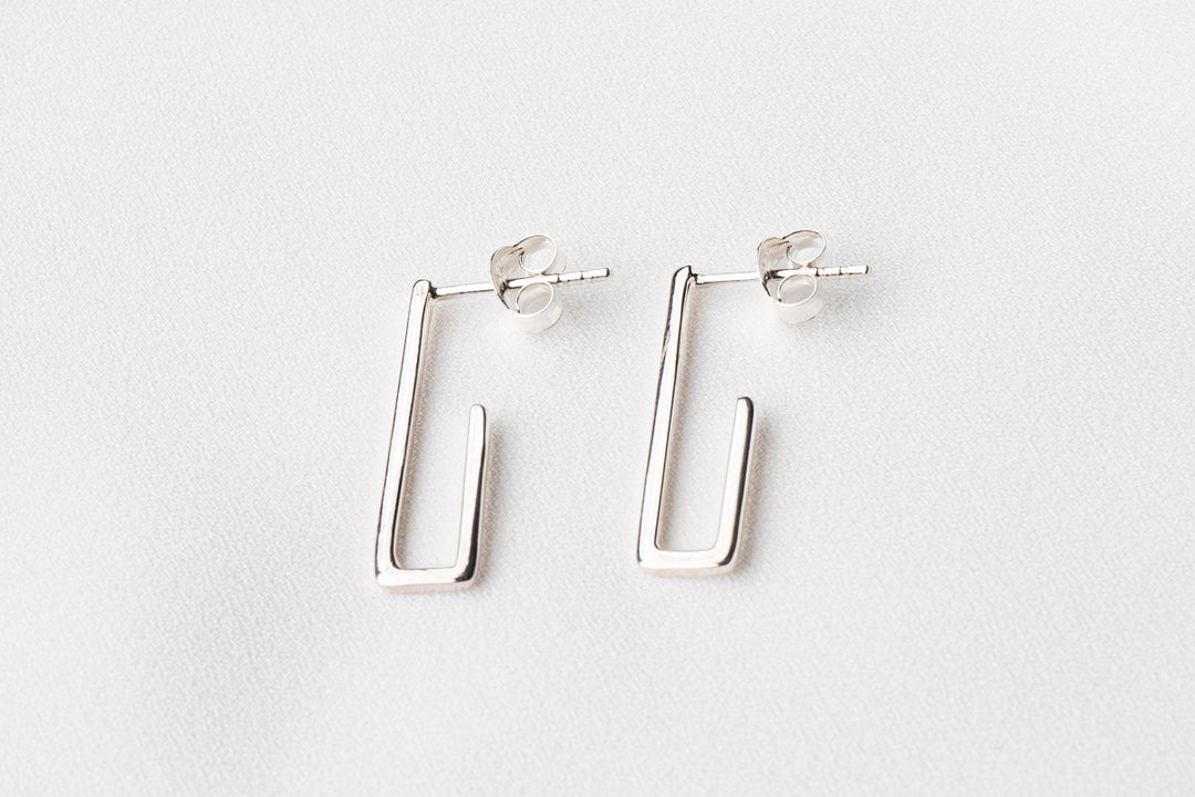 A pair of sterling silver dangle earrings with a butterfly back design on a white background.