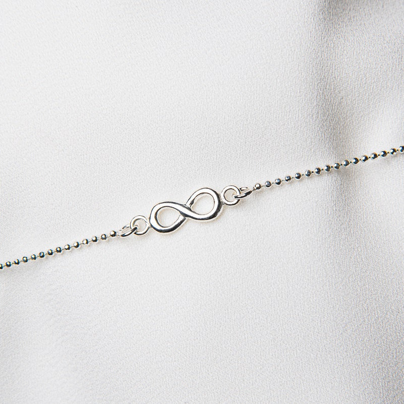 A sterling silver anklet featuring a beaded chain design with a infinity symbol pendant, displayed against a white background.
