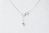 Fine chain drop style necklace with infinity pendant on a white background