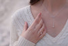 Fine chain drop style necklace with infinity pendant worn by a woman