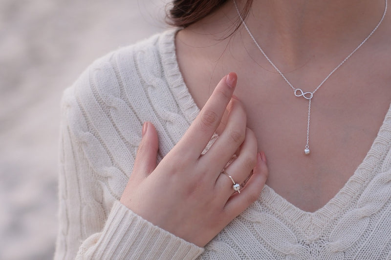 Fine chain drop style necklace with infinity pendant worn by a woman